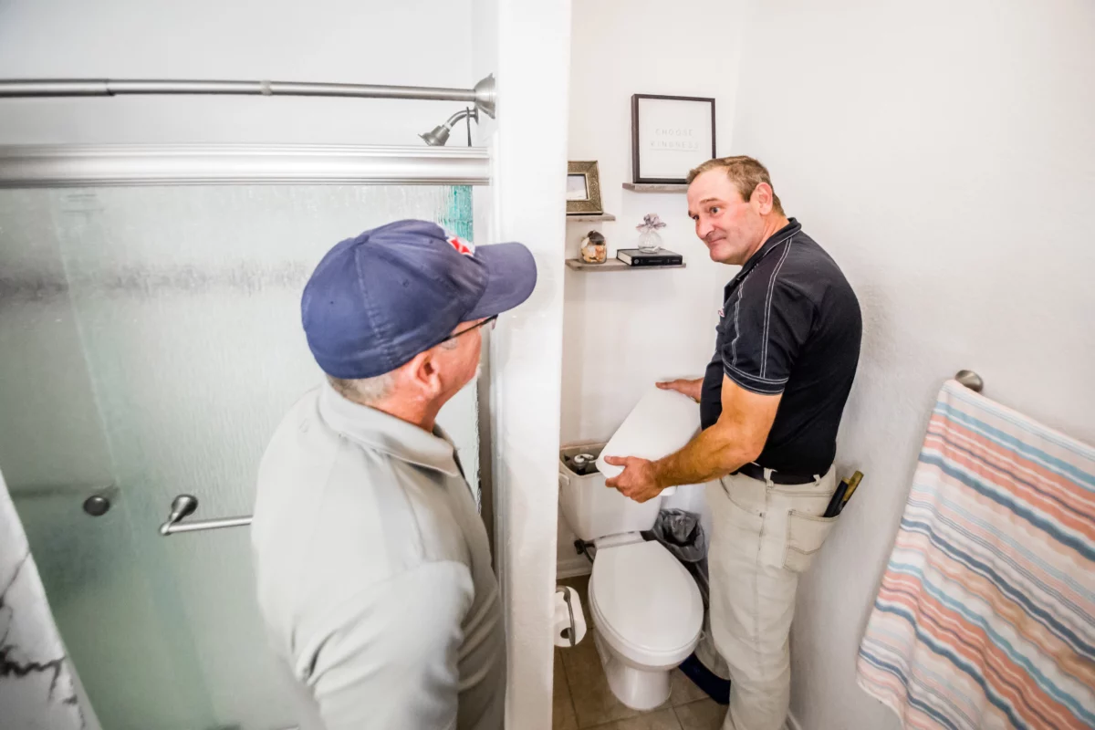 plumber inspecting toilet with the customer
